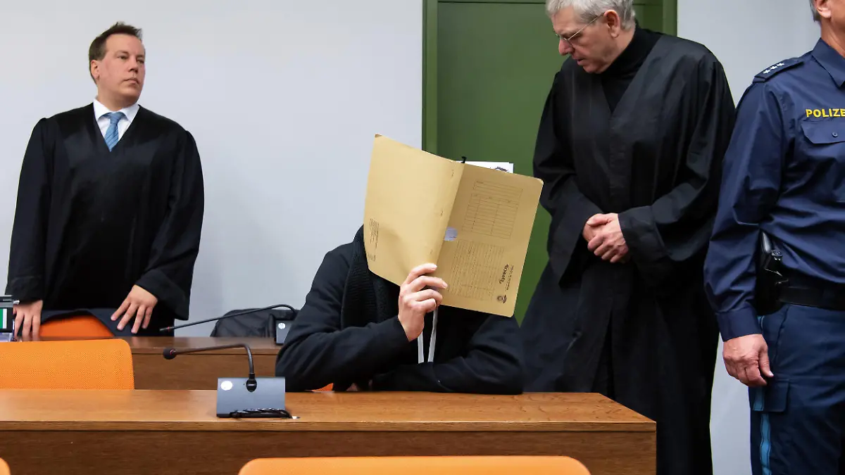 12.11.2019, Bayern, München: Der wegen versuchten Mordes an zahlreichen Frauen und Mädchen 30-jährige Angeklagte (2.v.l.)kommt vor Prozessbeginn im Landgericht zusammen mit seinen Anwälten Klaus Spiegel (2.v.r.) und Matthias Bohn (l) in den Sitzungssaal. Der Mann soll sich gegenüber jungen Frauen als Arzt ausgegeben und sie zu lebensgefährlichen Stromexperimenten gebracht haben. Teile des Bildes aus rechtlichen Gründen gepixelt. Foto: Sven Hoppe/dpa +++ dpa-Bildfunk +++