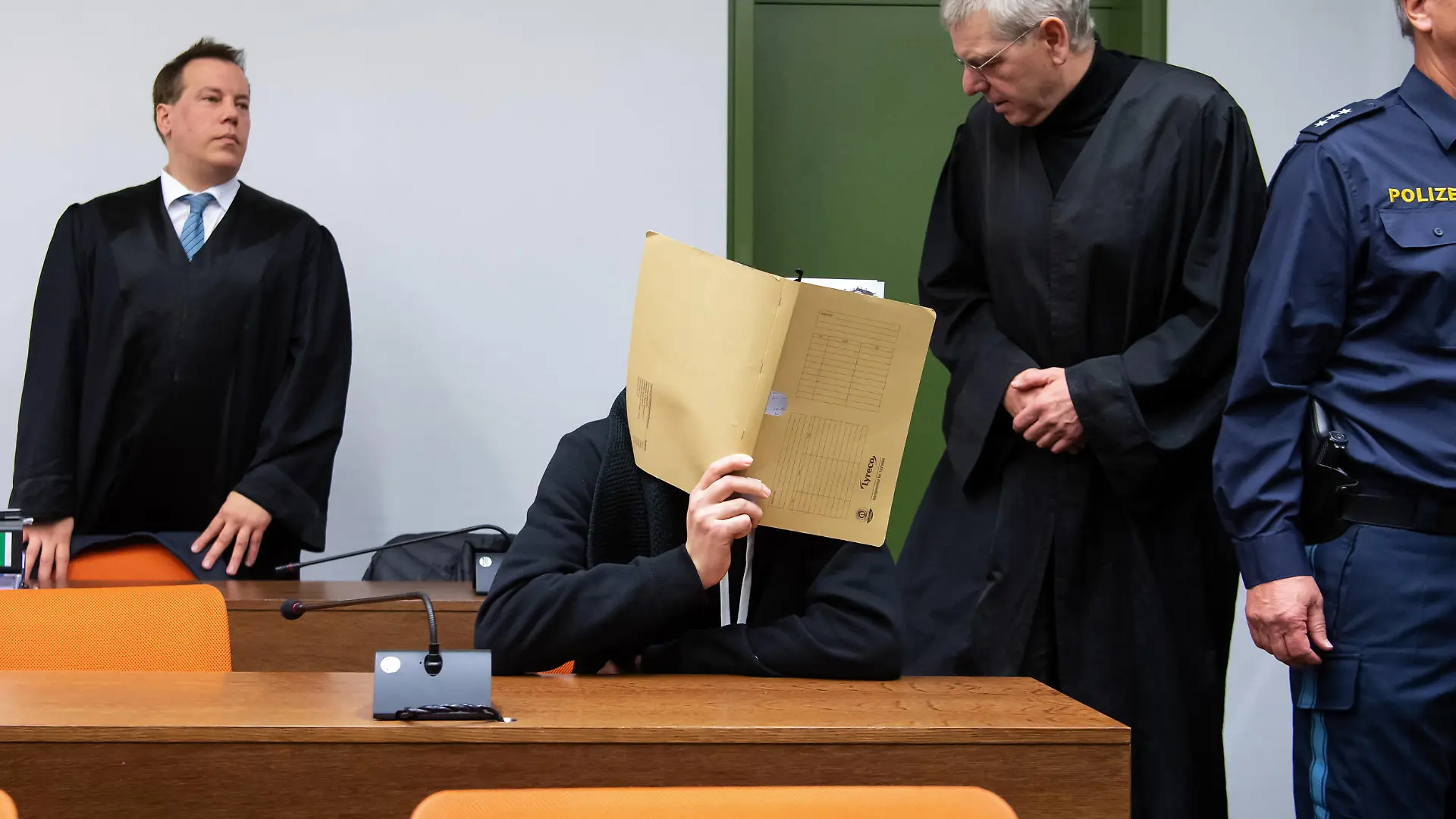 12.11.2019, Bayern, München: Der wegen versuchten Mordes an zahlreichen Frauen und Mädchen 30-jährige Angeklagte (2.v.l.)kommt vor Prozessbeginn im Landgericht zusammen mit seinen Anwälten Klaus Spiegel (2.v.r.) und Matthias Bohn (l) in den Sitzungssaal. Der Mann soll sich gegenüber jungen Frauen als Arzt ausgegeben und sie zu lebensgefährlichen Stromexperimenten gebracht haben. Teile des Bildes aus rechtlichen Gründen gepixelt. Foto: Sven Hoppe/dpa +++ dpa-Bildfunk +++
