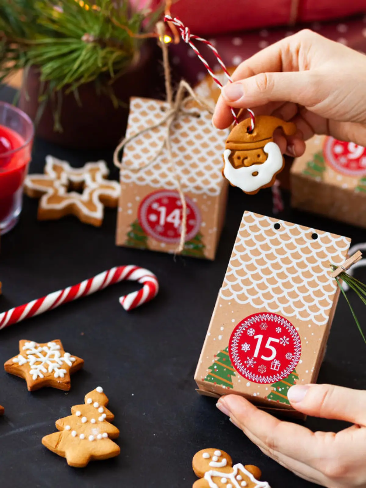 Woman preparing original Advent holiday calendar for Christmas or New year as countdown to Christmas Eve for kids. Zero waste paper package, homemade gingerbread cookies. Cozy home atmosphere