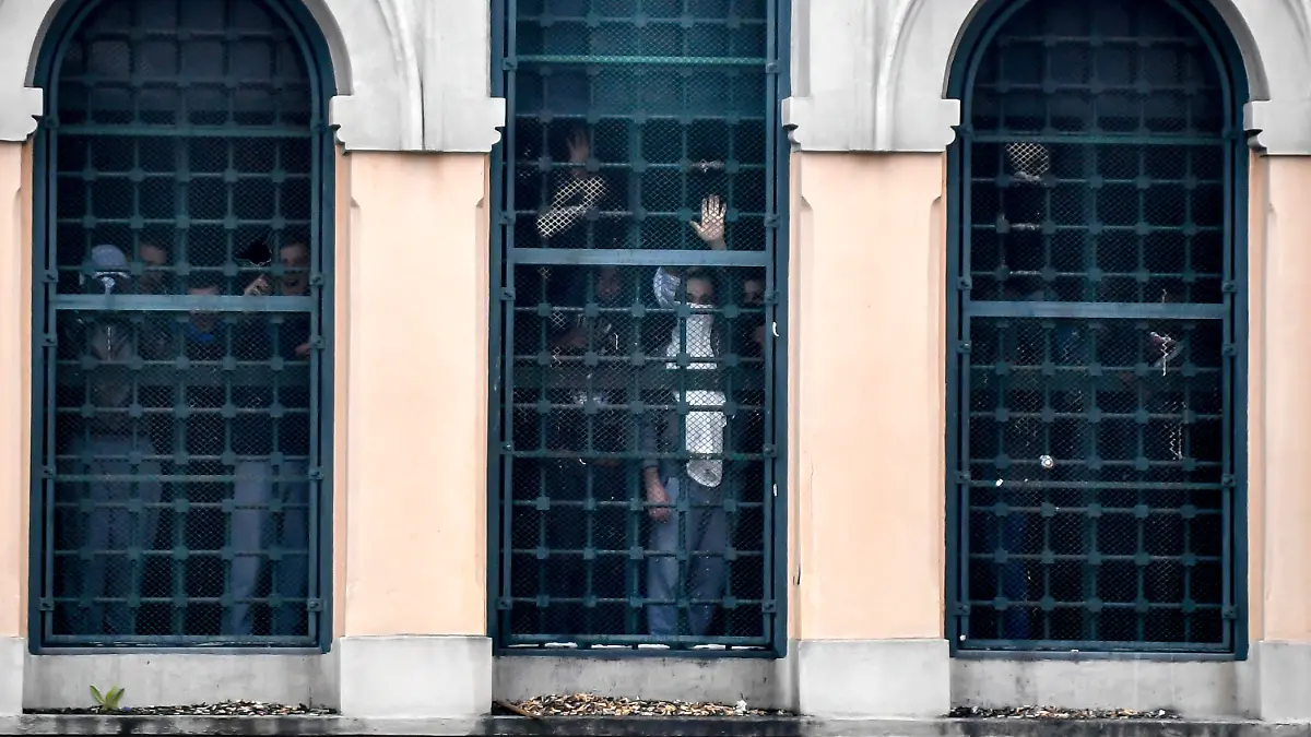 dpatopbilder - 09.03.2020, Italien, Mailand: Menschen stehen hinter den Fenstern eines Gefängnisses. Die Insassen des San-Vittore-Gefängnis rebellieren auf Grund der Maßnahmen gegen die Verbreitung des Coronavirus. Foto: Claudio Furlan/LaPresse/AP/dpa +++ dpa-Bildfunk +++