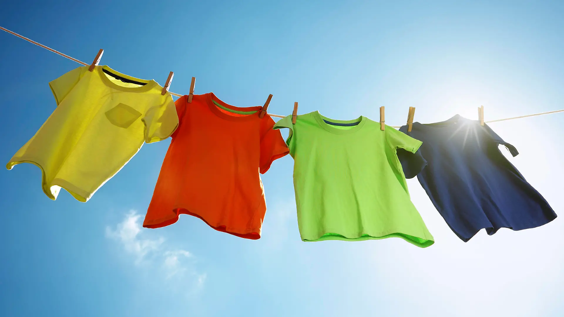 Wäsche, T-shirts hanging on a clothesline in front of blue sky and sun