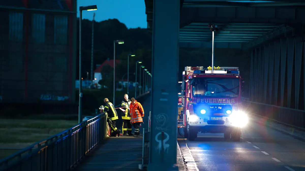 Ein Fahrzeug der Feuerwehr steht am 31.07.2015 bei Hohnstorf/Elbe (Niedersachsen) auf einer Brücke, die über die Elbe nach Lauenburg (Schleswig-Holstein) führt. Im Fall der verschwundenen Familie aus Drage (Niedersachsen) prüft die Polizei einen Zusammenhang mit einer in der Elbe in Lauenburg gefundenen männlichen Leiche. Foto: Philipp Schulze/dpa |