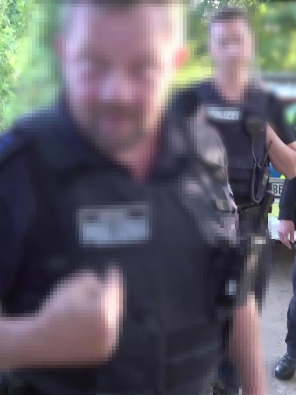Polizist reißt einen Kameramann zu Boden und würgt ihn.