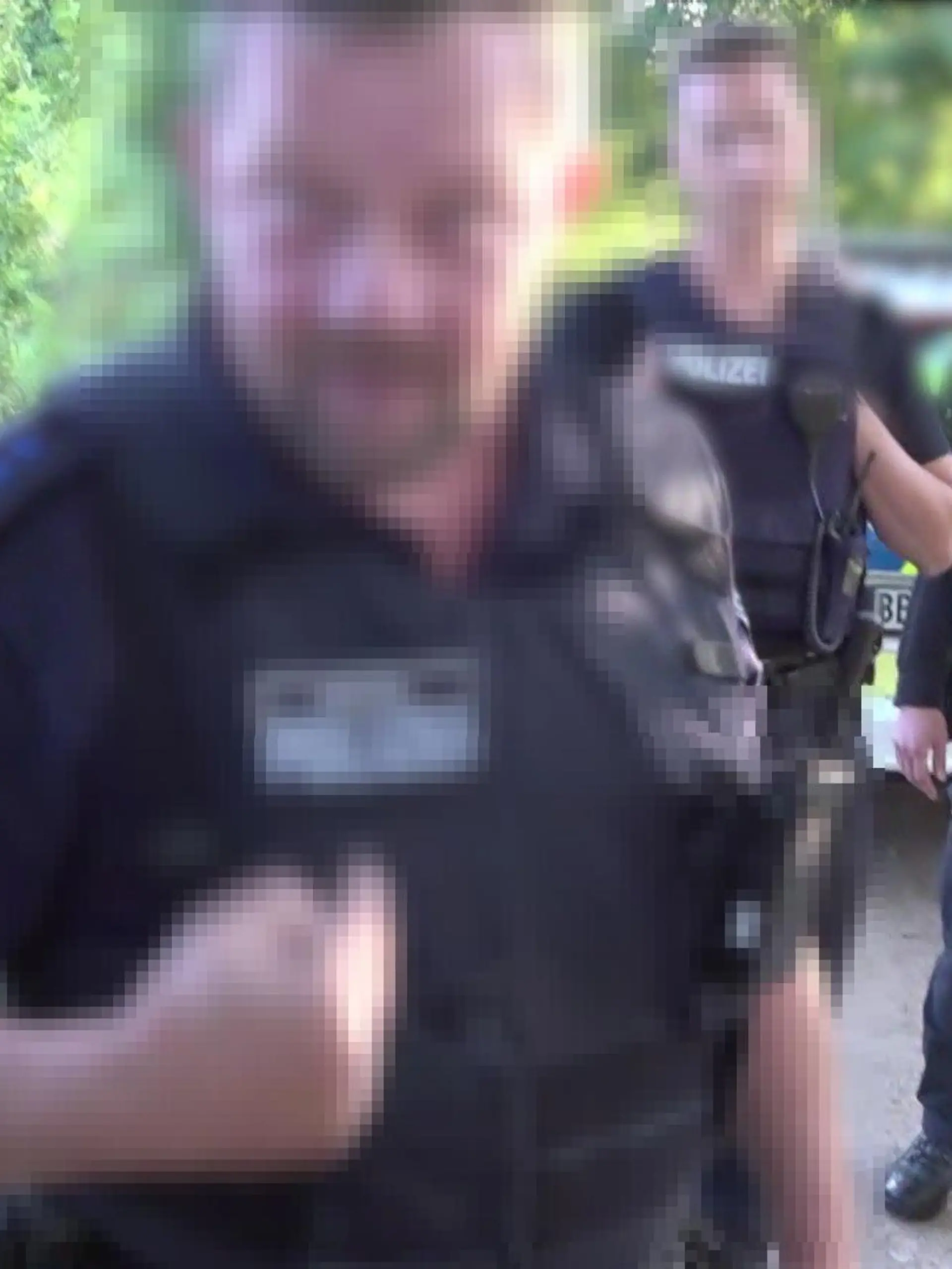 Polizist reißt einen Kameramann zu Boden und würgt ihn.
