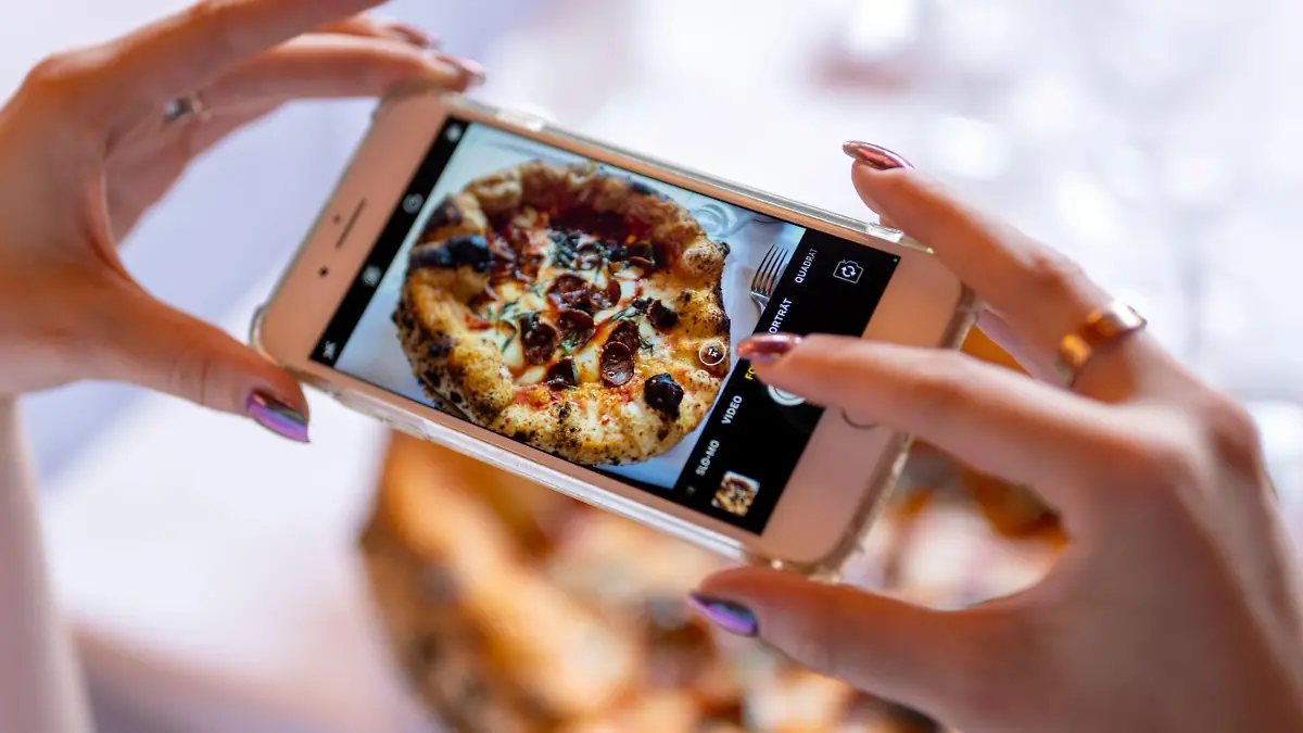 19.08.2022, Berlin: Eine Frau fotografiert mit ihrem Smartphone das Gericht «Drop it like it's hot» im Restaurant «Coccodrillo» im Weinbergspark. Hauptsache «instagrammable» scheint das Motto mancher neuer Lokale zu sein. (zu dpa-Korr «Überwältigend»: Wie die Instagramisierung der Gastrowelt weitergeht») Foto: Monika Skolimowska/dpa +++ dpa-Bildfunk +++