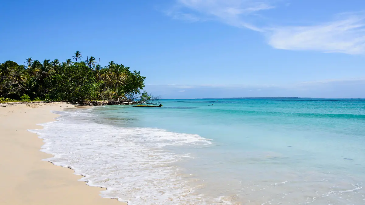 White sand beach on a tropical island in the archipelago of Bocas del Toro off the coast of Panama surrounded by a turquoise sea.
