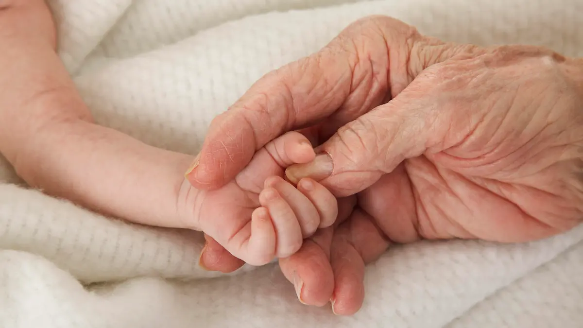 Ein neugeborenes Baby hält die Hand seiner Großmutter