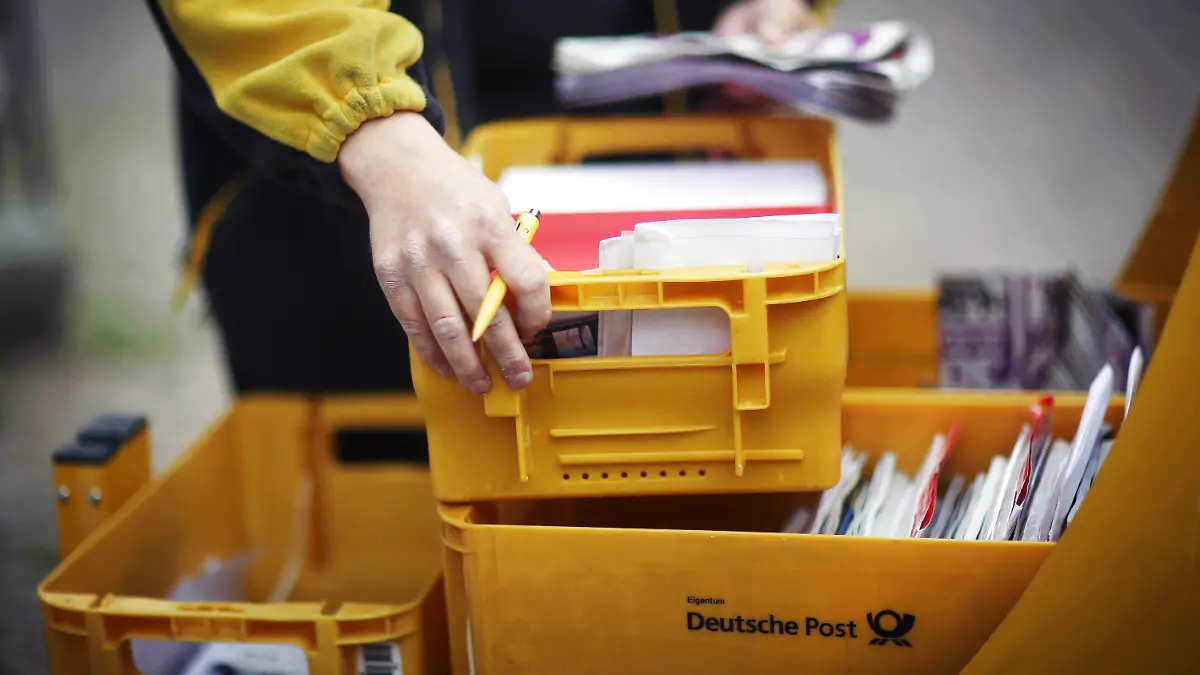 ARCHIV - Ein Mitarbeiter der Deutschen Post entnimmt am 09.06.2015 in Idstein (Hessen) Briefe aus seinem Briefzustellerwagen. Foto: Fredrik von Erichsen/dpa (zu dpa "Umfrage: Fast zwei Drittel haben Verständnis für Poststreik" vom 03.07.2015) +++(c) dpa - Bildfunk+++