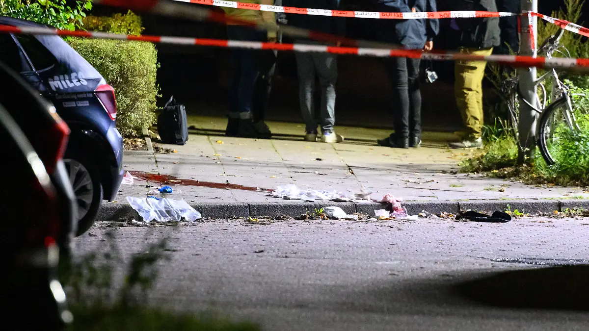 21.09.2022, Hamburg: Polizisten und Ermittler stehen am abgesperrten und ausgeleuchteten Tatort mit Blutspuren und Verbandsmaterial. Passanten haben in Hamburg-Veddel am Mittwochabend einen Mann mit Schussverletzungen am Kopf aufgefunden. Der Mann sei mit lebensgefährlichen Verletzungen in ein Krankenhaus gekommen, sagte ein Sprecher der Polizei Hamburg am frühen Donnerstagmorgen. Foto: Jonas Walzberg/dpa +++ dpa-Bildfunk +++