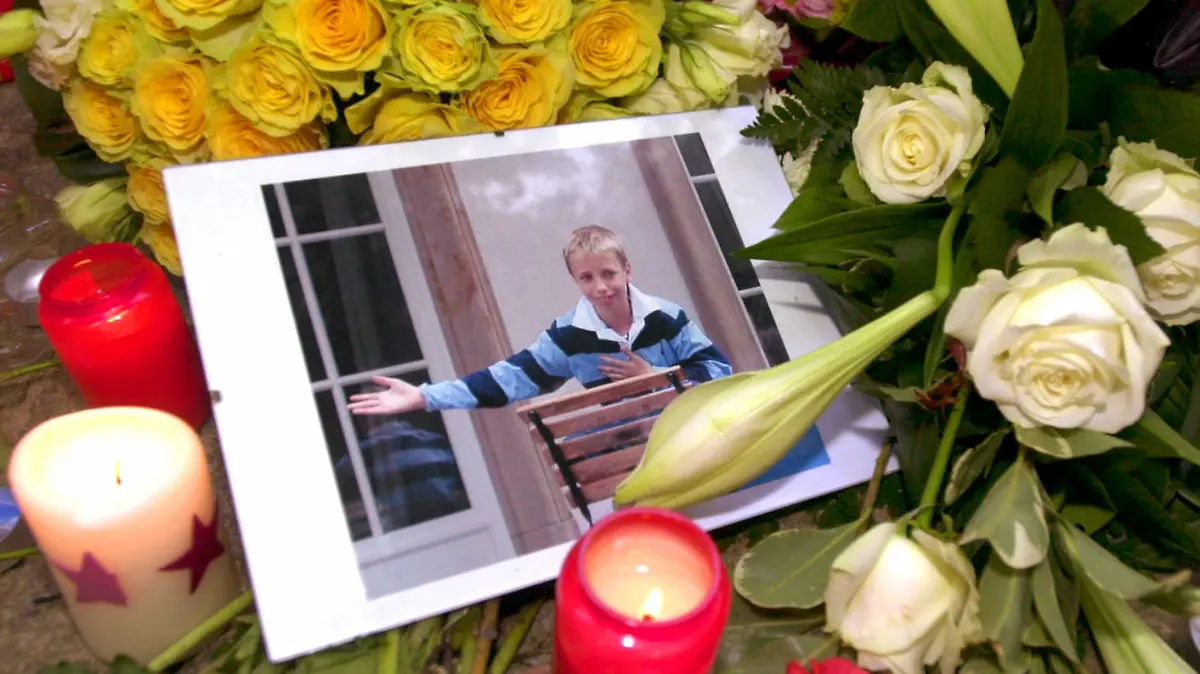 Inmitten von Blumengestecken und Kerzen liegt am 2.10.2002 vor dem Elternhaus des Mordopfers in Frankfurt am Main ein Bild des toten Jakob von Metzler. Die Leiche des Elfjährigen war am 1.10.2002 aus einem Waldsee bei Schlüchtern in Osthessen geborgen worden. Gegen den Hauptverdächtigen - einen 27- jährigen Jura-Studenten - erging mittlerweile Haftbefehl. Jakob war am 27.9.2002 auf dem Nachhauseweg von der Schule entführt worden.