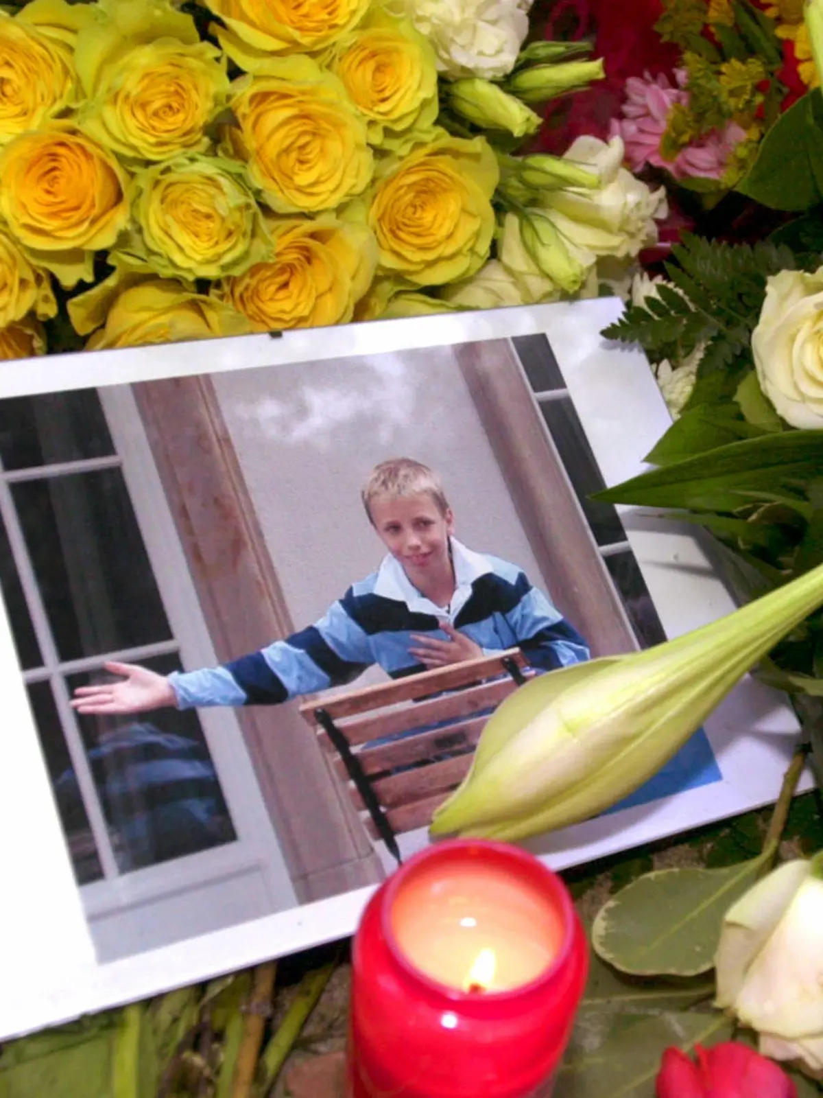 Inmitten von Blumengestecken und Kerzen liegt am 2.10.2002 vor dem Elternhaus des Mordopfers in Frankfurt am Main ein Bild des toten Jakob von Metzler. Die Leiche des Elfjährigen war am 1.10.2002 aus einem Waldsee bei Schlüchtern in Osthessen geborgen worden. Gegen den Hauptverdächtigen - einen 27- jährigen Jura-Studenten - erging mittlerweile Haftbefehl. Jakob war am 27.9.2002 auf dem Nachhauseweg von der Schule entführt worden.
