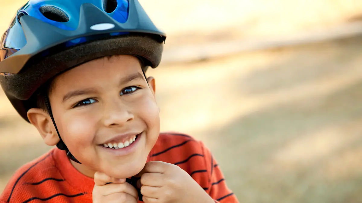 Little boy putting on his helmet.