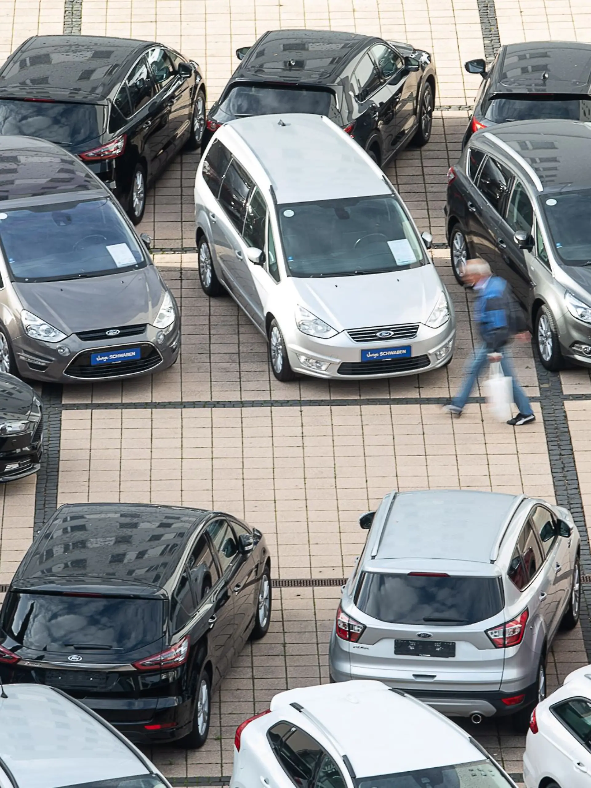 Ein Mann geht in einem Autohaus an Gebrauchtwagen vorbei.