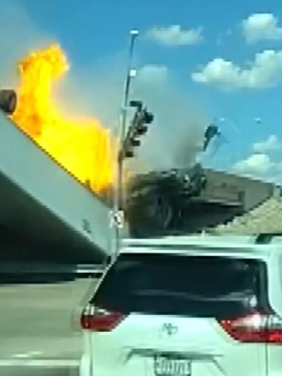 Ein Sattelschlepper stößt mit einem anderen Auto zusammen, Als er durch die Leitplanke kracht, fängt er Feuer und sürzt von der Brücke.