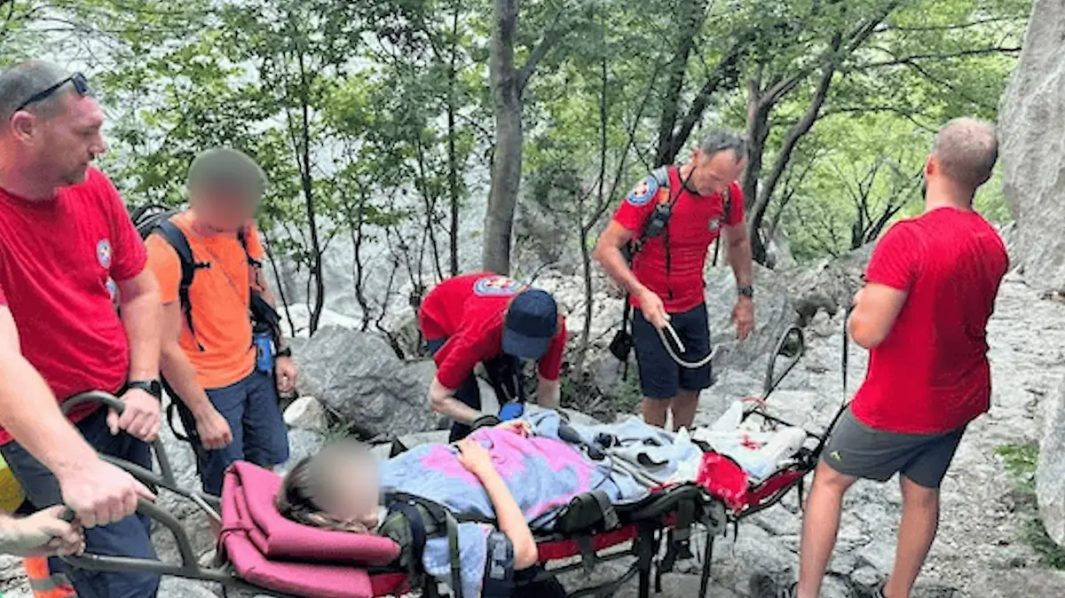 Eine Frau liegt auf einer Trage und wird von Rettungskräften getragen.