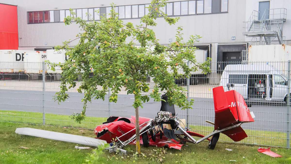 21.07.2021, Niedersachsen, Hildesheim: Ein zerstörter Tragschrauber liegt nach einem Absturz am Zaun eines Logistikzentrums in der Nähe des Hildesheimer Flugplatzes. Beim Absturz des Ultraleichtflugzeug sind zwei Menschen ums Leben gekommen. Foto: Julian Stratenschulte/dpa +++ dpa-Bildfunk +++