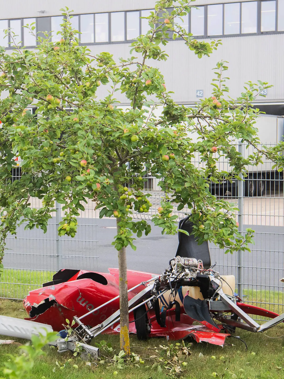 21.07.2021, Niedersachsen, Hildesheim: Ein zerstörter Tragschrauber liegt nach einem Absturz am Zaun eines Logistikzentrums in der Nähe des Hildesheimer Flugplatzes. Beim Absturz des Ultraleichtflugzeug sind zwei Menschen ums Leben gekommen. Foto: Julian Stratenschulte/dpa +++ dpa-Bildfunk +++