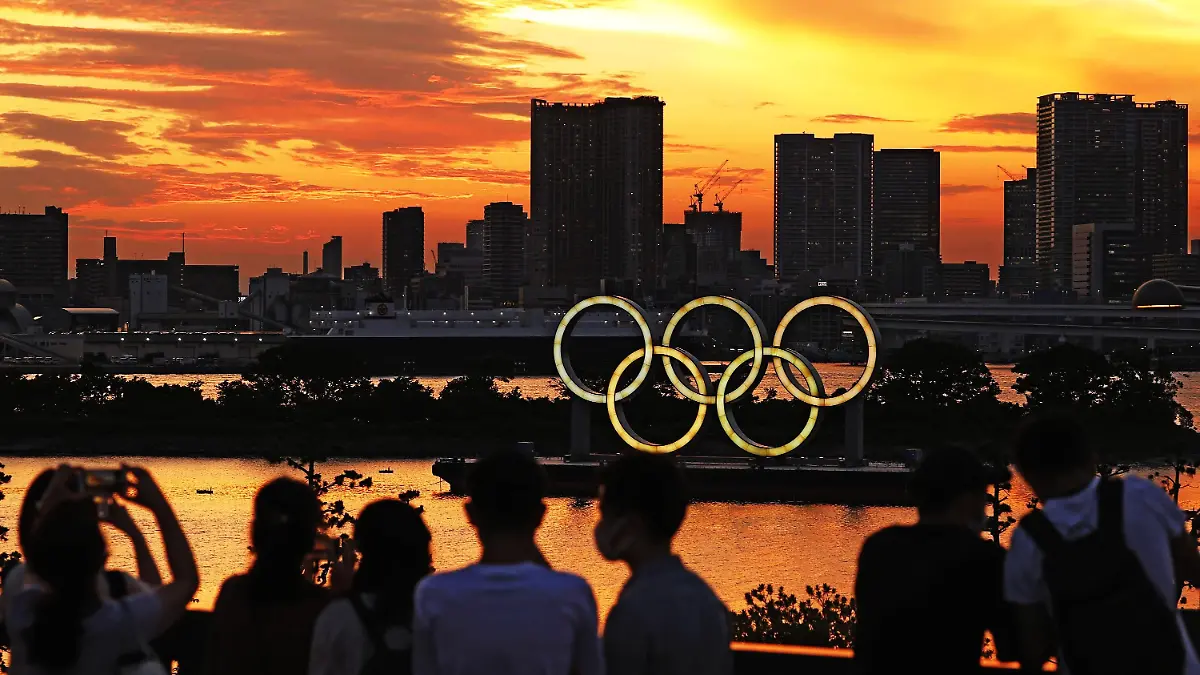 dpatopbilder - 21.07.2021, Japan, Tokio: Menschen schauen auf die bei Sonnenuntergang beleuchteten olympischen Ringe in der Bucht von Tokio. Foto: -/kyodo/dpa +++ dpa-Bildfunk +++