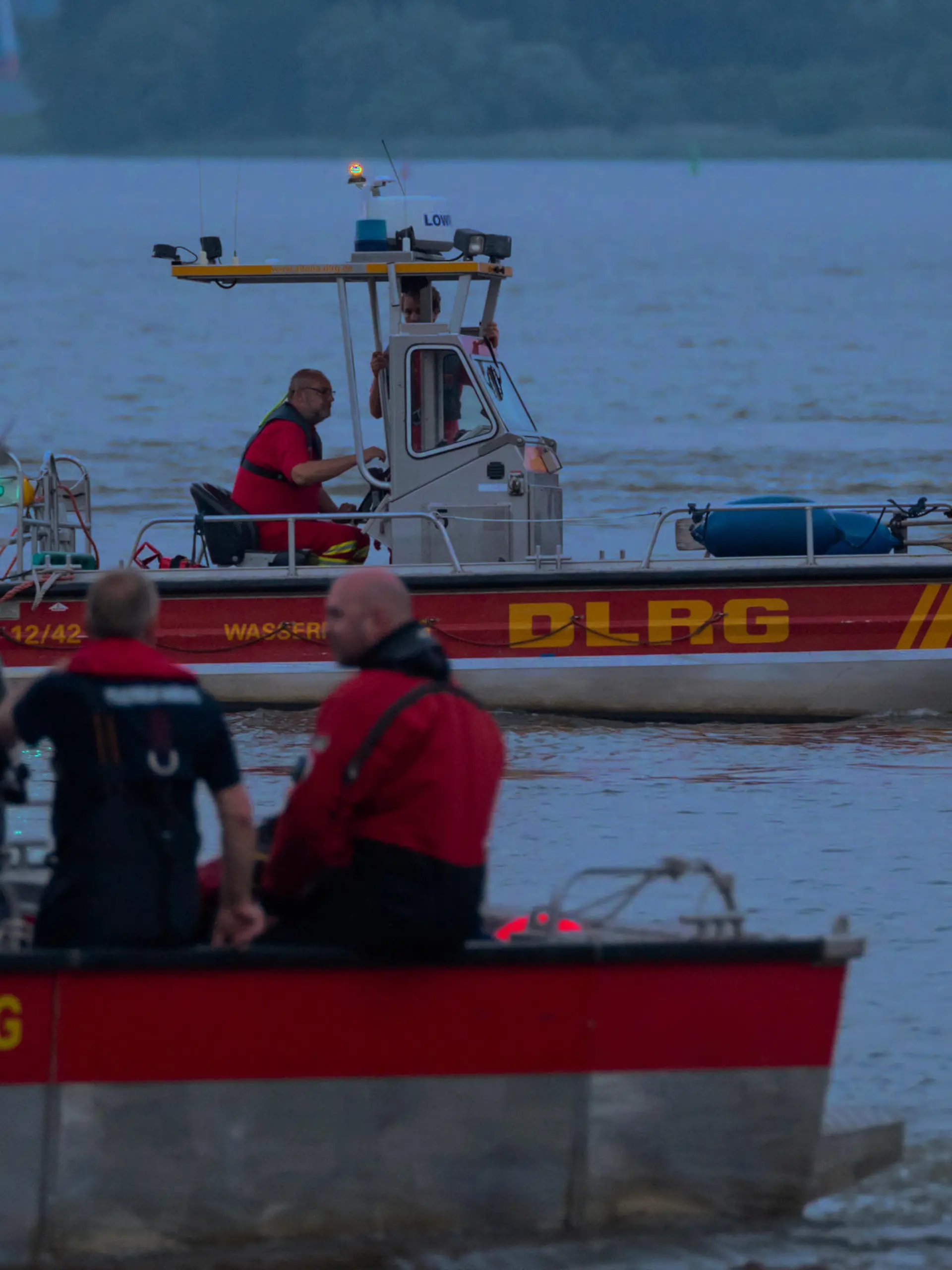 18.06.2021, Hamburg: Kleinboote von DLRG und Feuerwehr fahren bei der Suche über die Elbe. Feuerwehr und Polizei haben am Abend zweieinhalb Stunden nach einem jungen Mann gesucht, der von einem Signalturm in die Elbe gesprungen und nicht mehr aufgetaucht war. Sein Begleiter konnte laut Polizei aus dem Wasser gerettet werden. Foto: Jonas Walzberg/dpa +++ dpa-Bildfunk +++