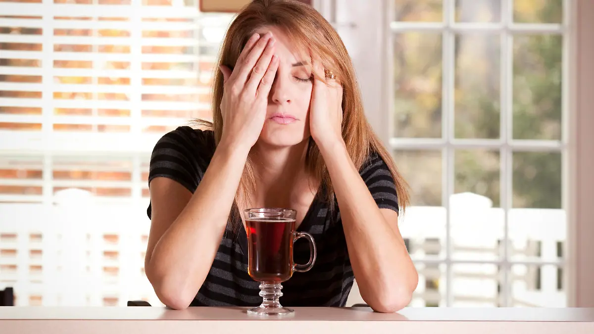 A woman with a cup of tea having a hard time waking up in the morning.