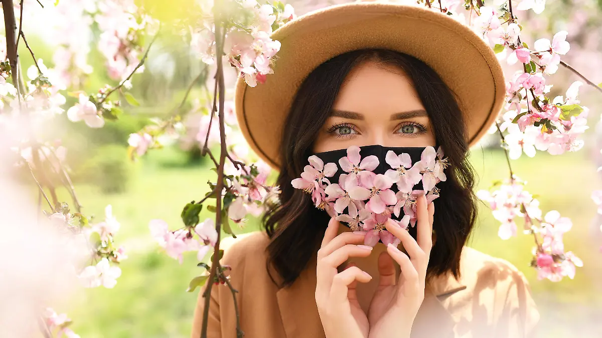 Woman wearing face mask decorated with flowers. Stylish handmade cotton mask. Spring blossom garden