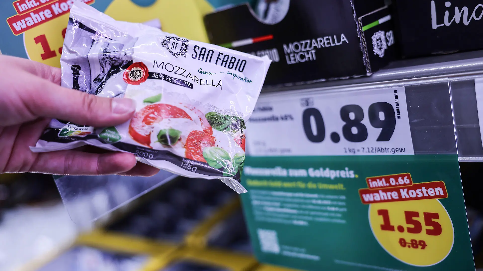 PRODUKTION - 26.07.2023, Nordrhein-Westfalen, Köln: Zwei Preisschilder hängen im Kühlregal vor einem Karton mit Mozzarella. Penny sorgt ab Montag (31.0.07.2023) für einen Preisschock der eigenen Art. Für neun Produkte kassiert das Unternehmen die «wahren Preise». Dabei werden auch verdeckte Kosten etwa für Umweltverschmutzung bei der Produktion berücksichtigt. (Zu dpa: «Discounter-Experiment: Wie teuer Lebensmittel eigentlich sei müssten») Foto: Oliver Berg/dpa +++ dpa-Bildfunk +++