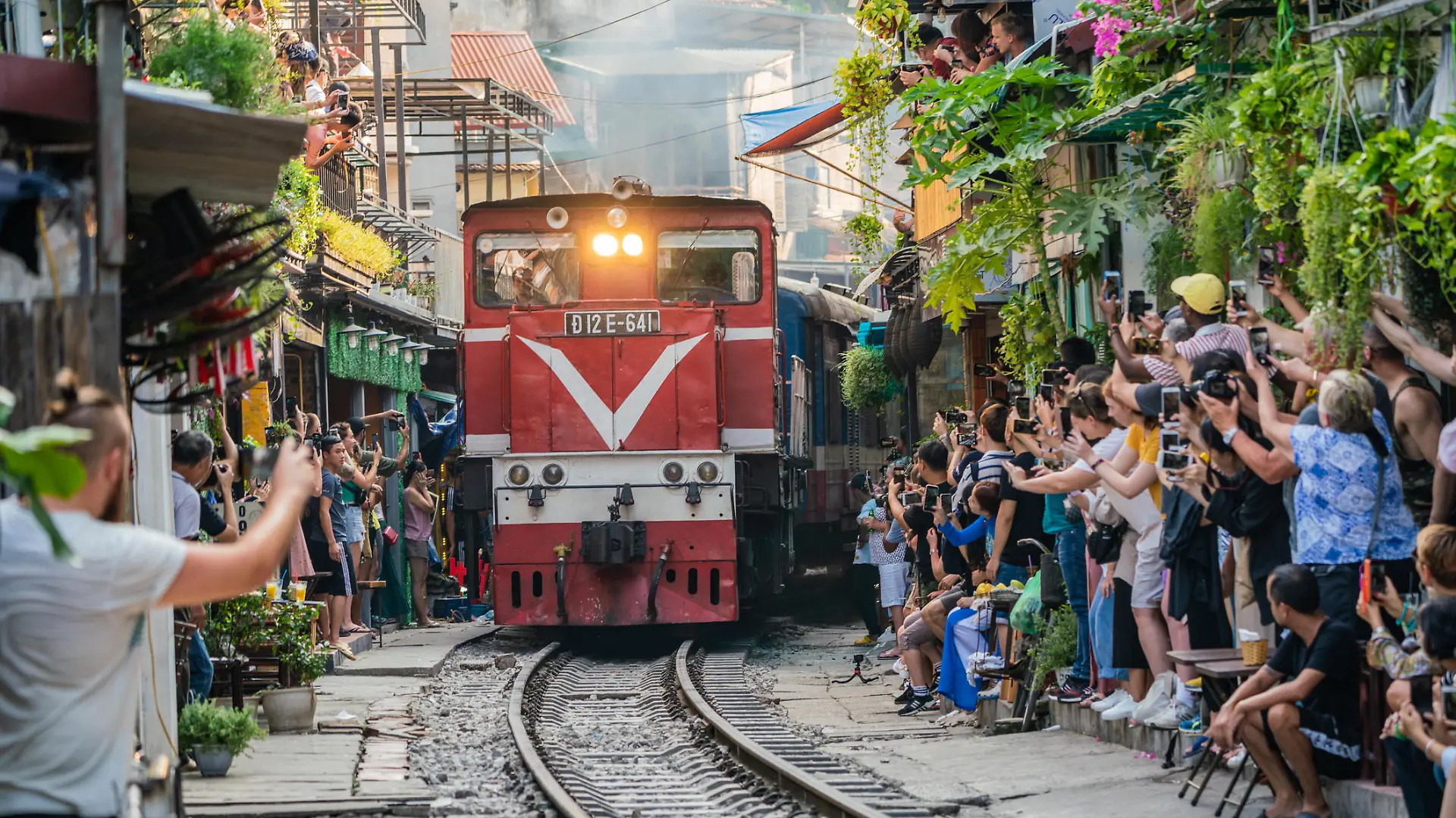 HANOI, VIETNAM - OCT 6, 2019 : View of train passing through a narrow street of the Hanoi Old Quarter. Tourists taking pictures of hurtling train. The Hanoi Train Street is a popular attraction.
