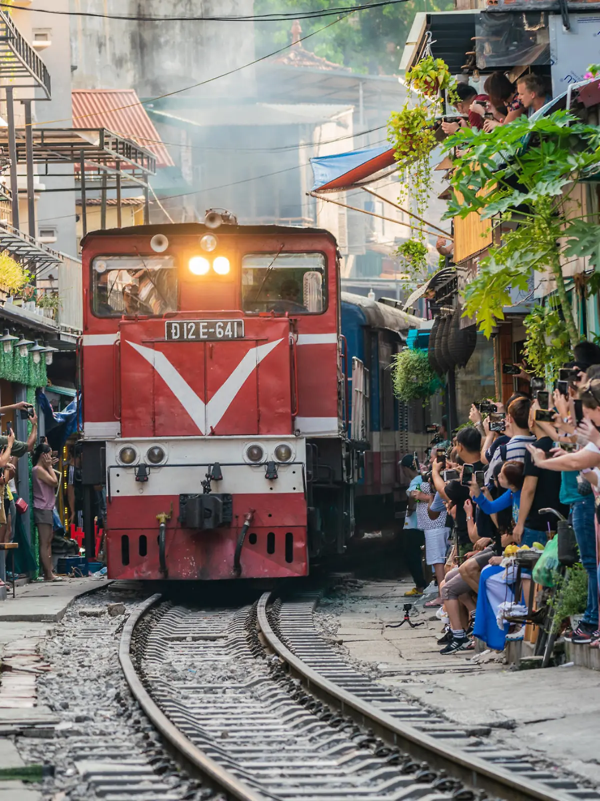 HANOI, VIETNAM - OCT 6, 2019 : View of train passing through a narrow street of the Hanoi Old Quarter. Tourists taking pictures of hurtling train. The Hanoi Train Street is a popular attraction.
