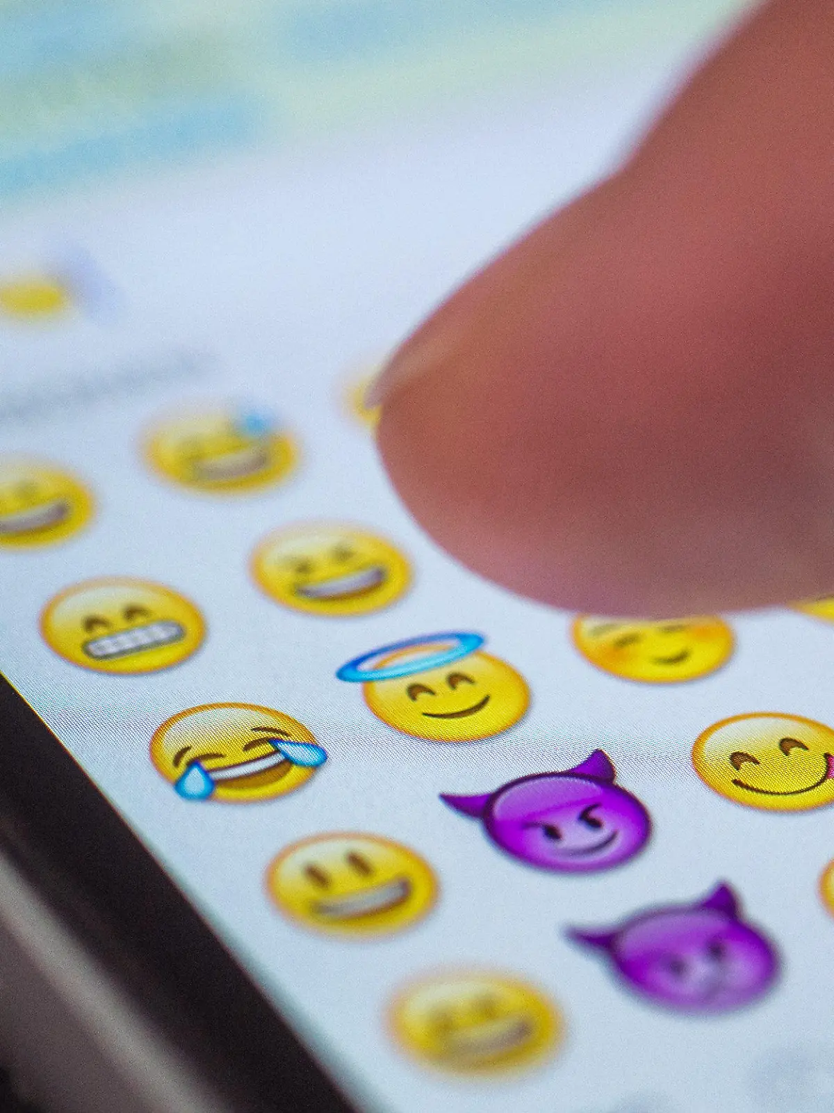 ARCHIV - ILLUSTRATION - Eine Frau tippt am 24.08.2015 in München (Bayern) auf das Display eines Smartphones, auf dem zahlreiche Emojis in der Nachrichten-App "Whatsapp" zu sehen sind. Oxford Dictionaries haben erstmals ein Emoji zum Wort des Jahres gewählt. Eher konservative Sprachpfleger mögen den Kopf schütteln - doch die Wahl 2015 fiel auf das berühmten «Smileygesicht  mit den Freudentränen». Foto: Matthias Balk/dpa (zu dpa "Oxford Dictionaries kürt Freudentränen-Emoji zum Wort des Jahres" vom 17.11.2015) +++(c) dpa - Bildfunk+++