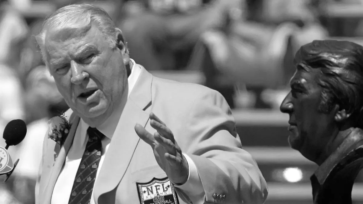 ARCHIV - 05.08.2006, USA, Canton: John Madden, ehemaliger Trainer der Oakland Raiders, gestikuliert während seiner Aufnahme in die Pro Football Hall of Fame in Canton, Ohio, in Richtung einer Büste von ihm. Die Football-Welt trauert um John Madden. Die Trainer- und Kommentatorenlegende ist am Dienstag, 28.12.2021, im Alter von 85 Jahren gestorben. Foto: Mark Duncan/AP/dpa +++ dpa-Bildfunk +++