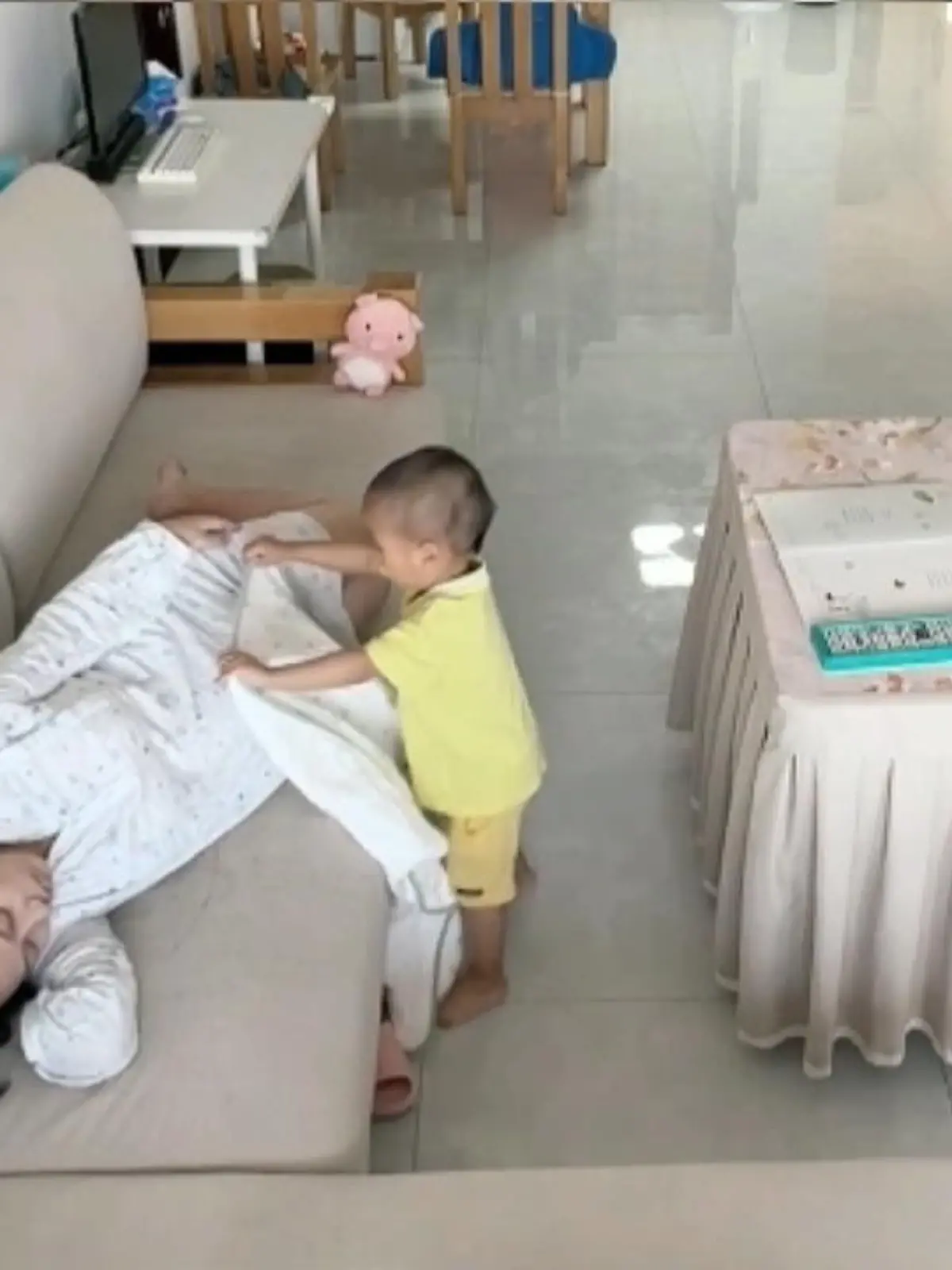 Ein 2-Jähriger in Shenzhen in China legt eine Decke über seine schwangere Mutter. Anschließend streichelt und küsst er ihren Bauch.