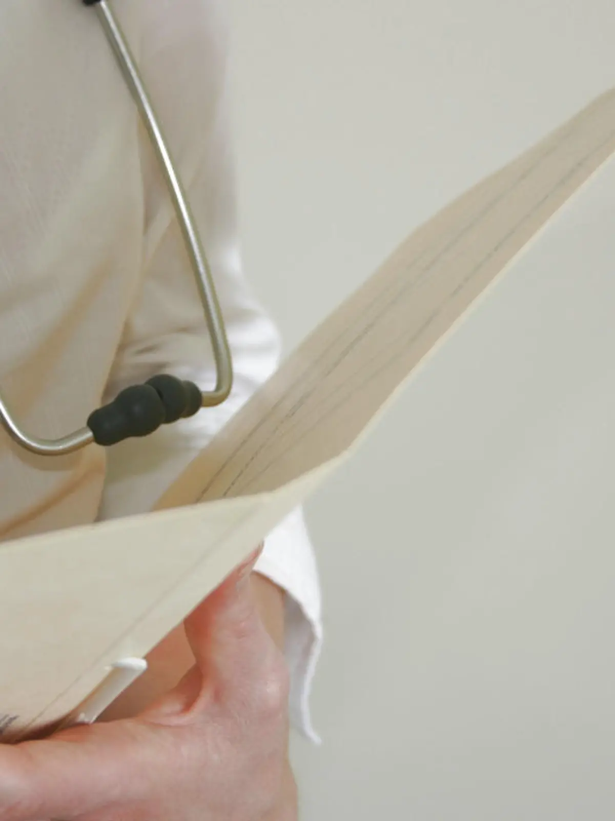 Closeup of female doctor (Caucasian) with stethoscope writing in patient chart