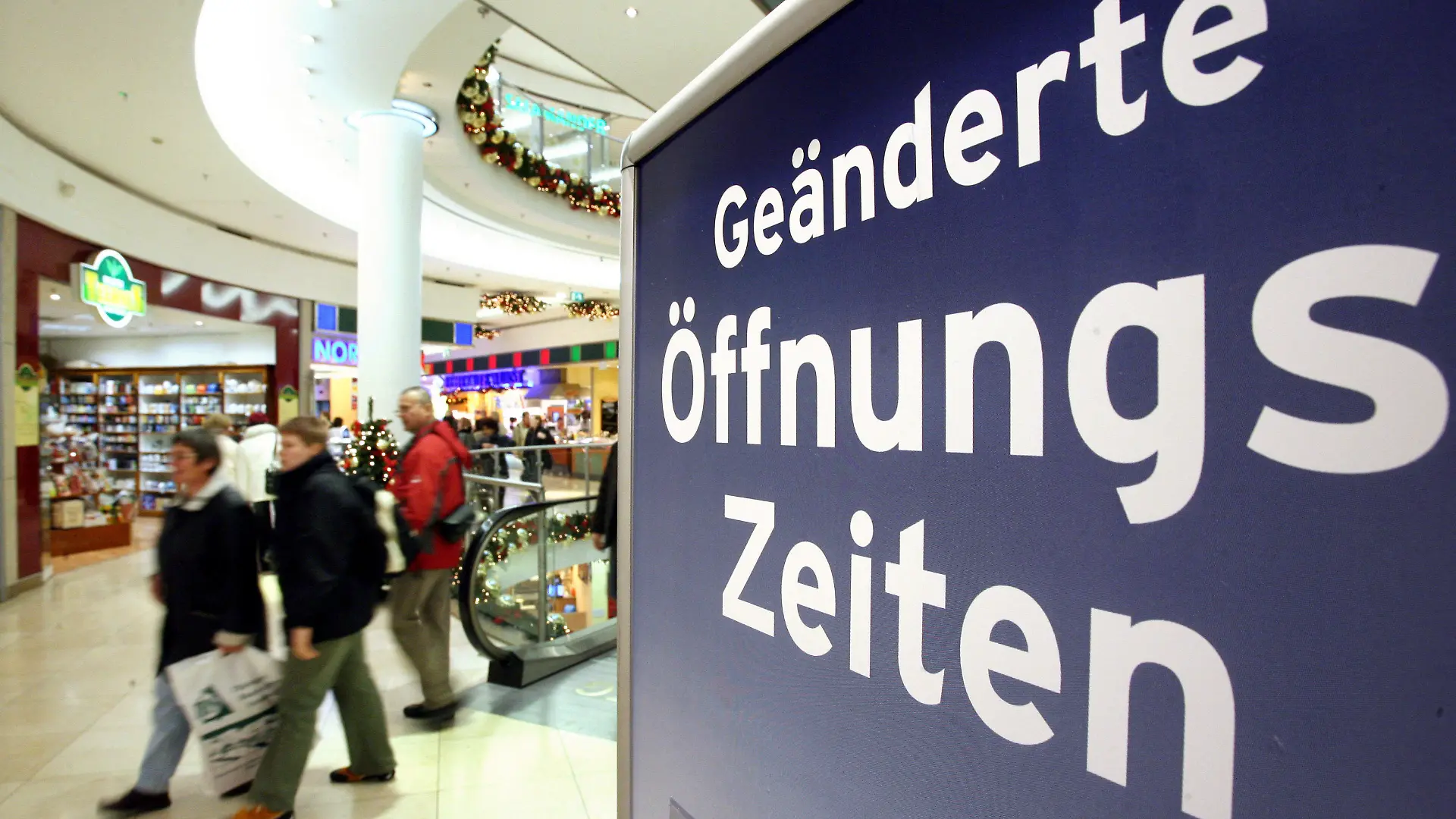 ARCHIV - Auf einem Plakat wird im Einkaufszentrum in Erfurt auf die veränderten Ladenöffnungszeiten hingewiesen, aufgenommen am 30.11.2006. Am Mittwoch (18.01.2012) findet in Düsseldorf eine Expertenanhörung im Wirtschaftsausschuss des Landtags zur Evaluierung des Ladenöffnungs-Gesetzes statt. Foto: Martin Schutt/lnw +++(c) dpa - Bildfunk+++