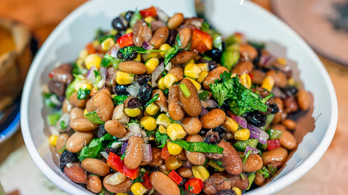 Macro closeup with texture of bean salad with cilantro, red onion, raisins, peppers and corn as dinner meal for family with bokeh background
