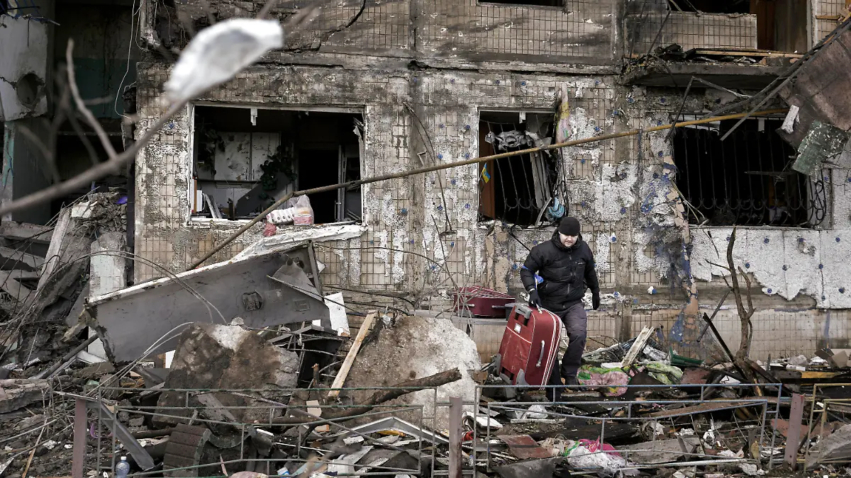 14.03.2022, Ukraine, Kiew: Ein Mann trägt einen Koffer aus einem durch Artilleriebeschuss zerstörten Wohngebäude. Die russischen Streitkräfte setzen ihre Angriffe auf die ukrainischen Hauptstadt fort, nachdem ein Luftangriff auf einen Militärstützpunkt in der Nähe der polnischen Grenze den Krieg gefährlich nahe an das NATO-Gebiet gebracht hat. Foto: Vadim Ghirda/AP/dpa +++ dpa-Bildfunk +++