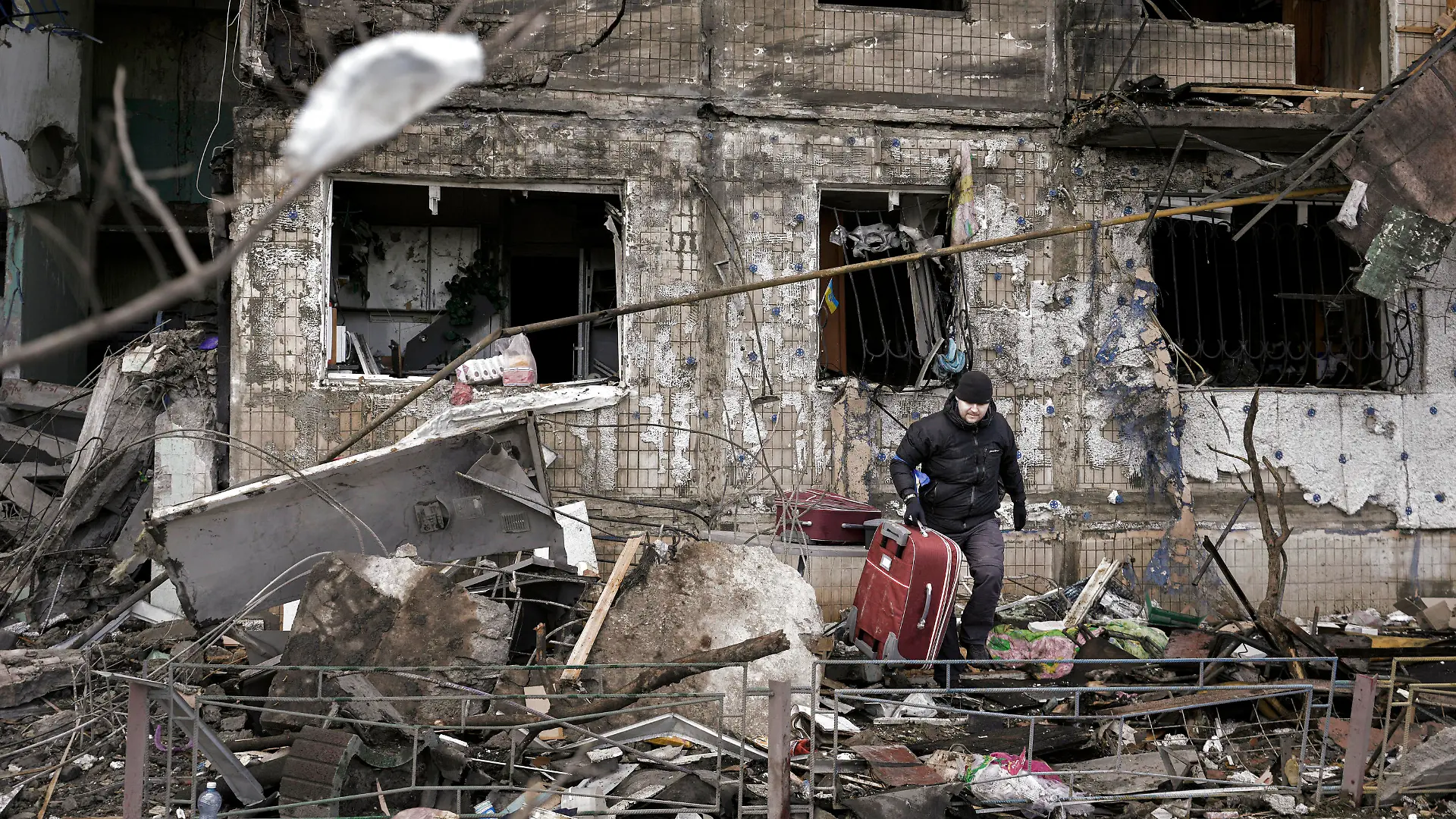 14.03.2022, Ukraine, Kiew: Ein Mann trägt einen Koffer aus einem durch Artilleriebeschuss zerstörten Wohngebäude. Die russischen Streitkräfte setzen ihre Angriffe auf die ukrainischen Hauptstadt fort, nachdem ein Luftangriff auf einen Militärstützpunkt in der Nähe der polnischen Grenze den Krieg gefährlich nahe an das NATO-Gebiet gebracht hat. Foto: Vadim Ghirda/AP/dpa +++ dpa-Bildfunk +++
