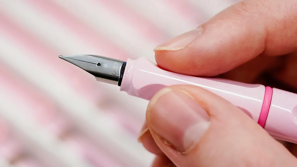 Eine Mitarbeiterin hält am Hauptsitz des Schreibgeräteherstellers Lamy einen Füllfederhalter in den Händen.
