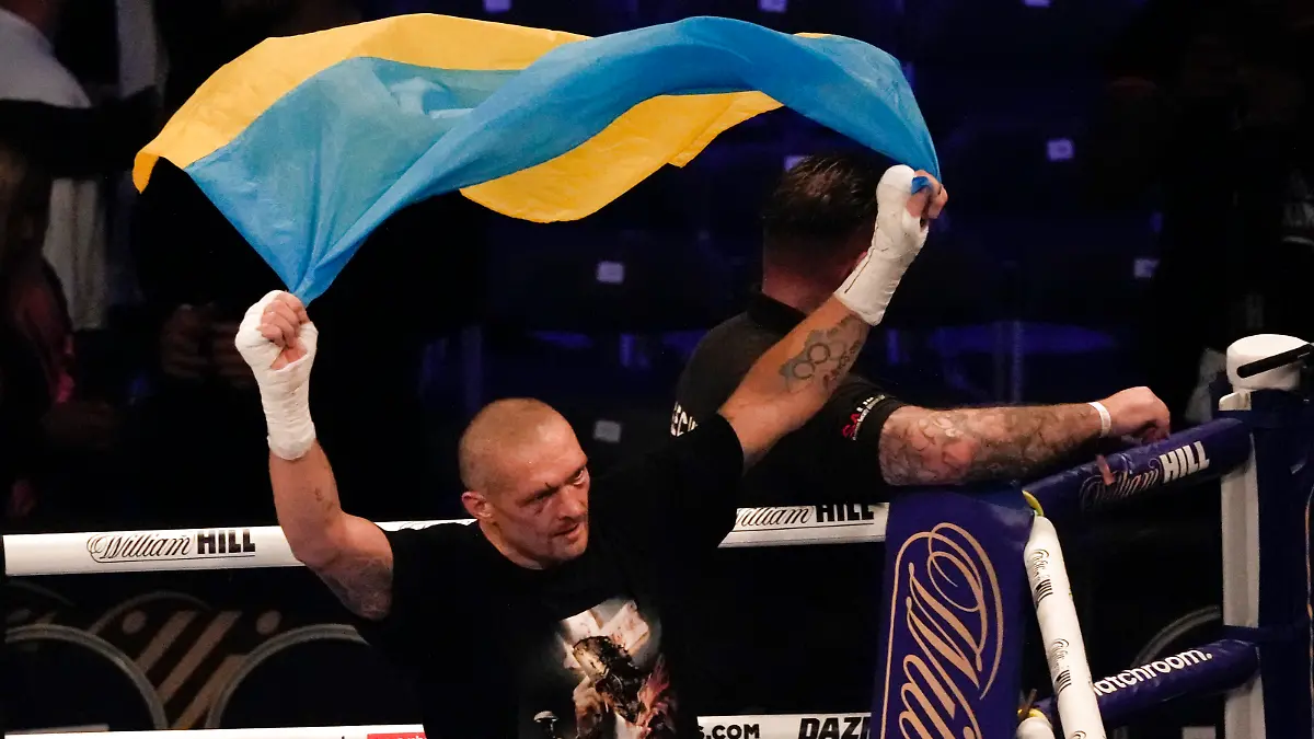 Oleksandr Usyk of Ukraine holds up the Ukrainian flag after his unanimous decision victory over Anthony Joshua of Britain in their WBA (Super), WBO and IBF boxing title bout at the Tottenham Hotspur Stadium in London, Saturday, Sept. 25, 2021. (AP Photo/Frank Augstein)