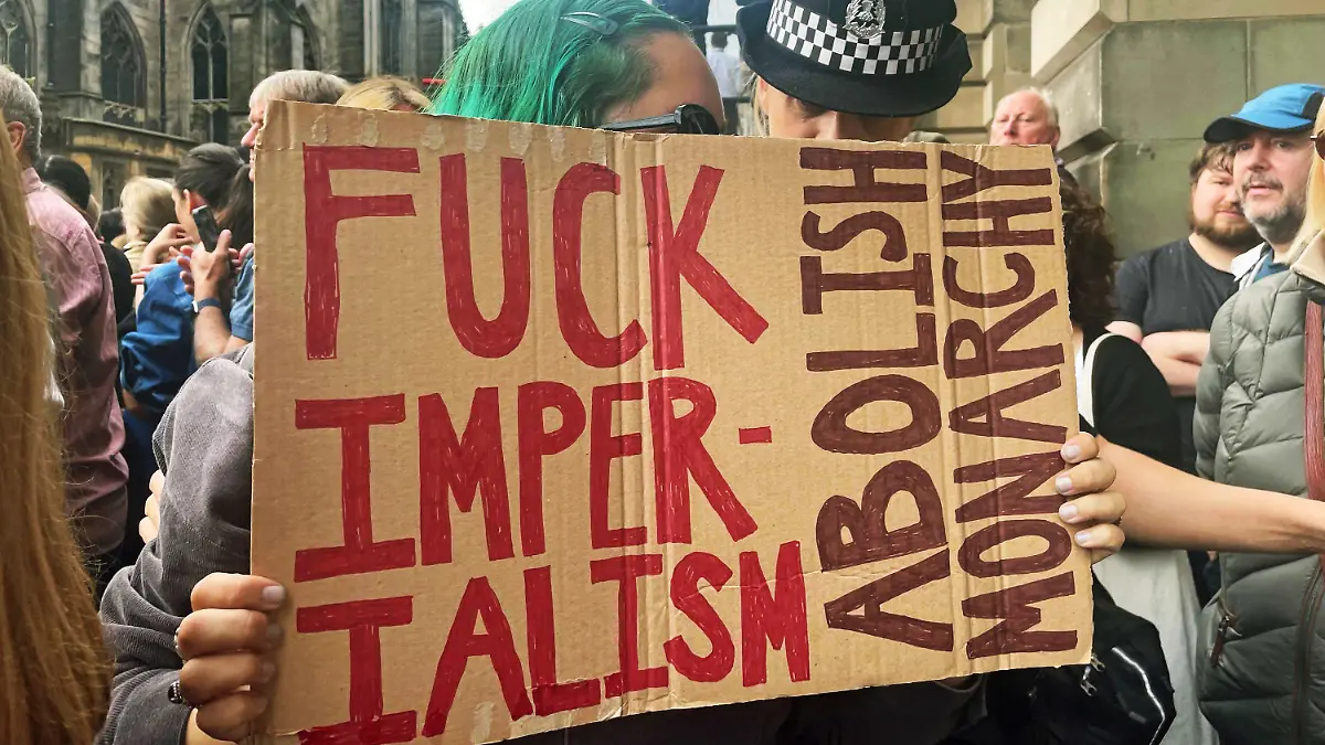 11.09.2022, Großbritannien, Edinburgh: Eine Polizistin spricht mit einer jungen Frau, die ein Schild mit der Aufschrift "Fuck Imperialism - Abolish monarchy" während der Proklamationszeremonie von König Charles III. zur Thronbesteigung am Mercat Cross hält. Es gibt durchaus Briten, die weder mit dem Trubel um den Tod der Queen noch mit der Monarchie insgesamt etwas anfangen können. (zu dpa-Korr "Monarchiegegner und Royal-Muffel: Nicht alle trauern um die Queen") Foto: Isobel Frodsham/PA Wire/dpa +++ dpa-Bildfunk +++