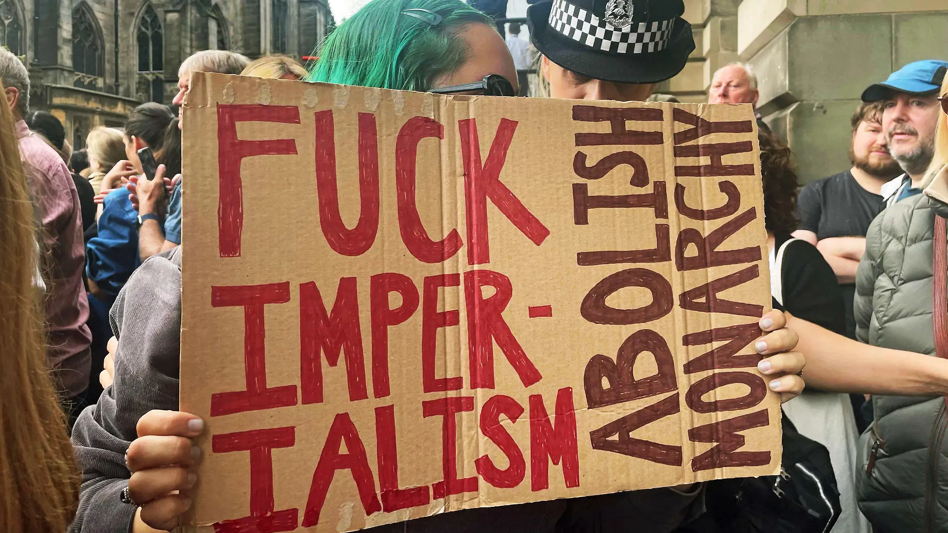 11.09.2022, Großbritannien, Edinburgh: Eine Polizistin spricht mit einer jungen Frau, die ein Schild mit der Aufschrift "Fuck Imperialism - Abolish monarchy" während der Proklamationszeremonie von König Charles III. zur Thronbesteigung am Mercat Cross hält. Es gibt durchaus Briten, die weder mit dem Trubel um den Tod der Queen noch mit der Monarchie insgesamt etwas anfangen können. (zu dpa-Korr "Monarchiegegner und Royal-Muffel: Nicht alle trauern um die Queen") Foto: Isobel Frodsham/PA Wire/dpa +++ dpa-Bildfunk +++
