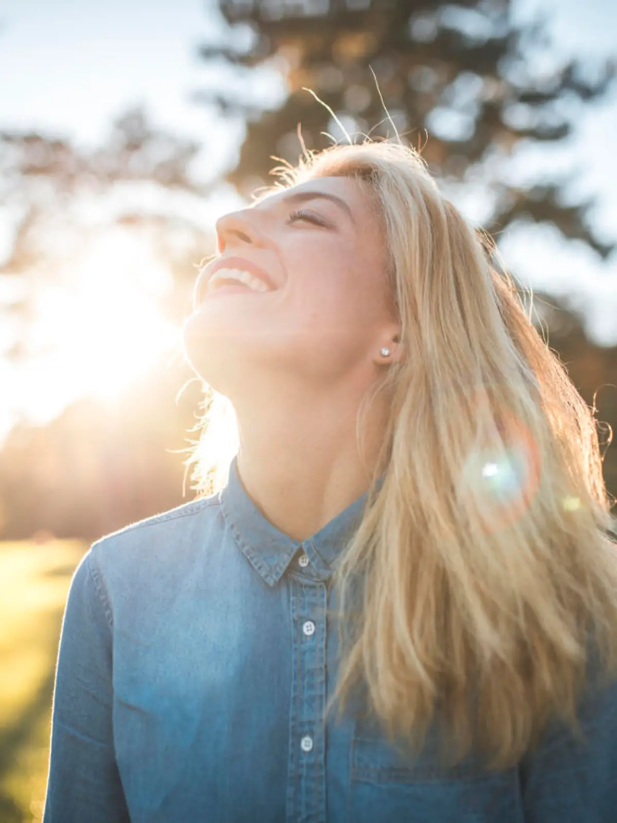 Woman enjoying in a park on a sunny summer day. She have her eyes closed, she is smiling and enjoying fresh air and sun.