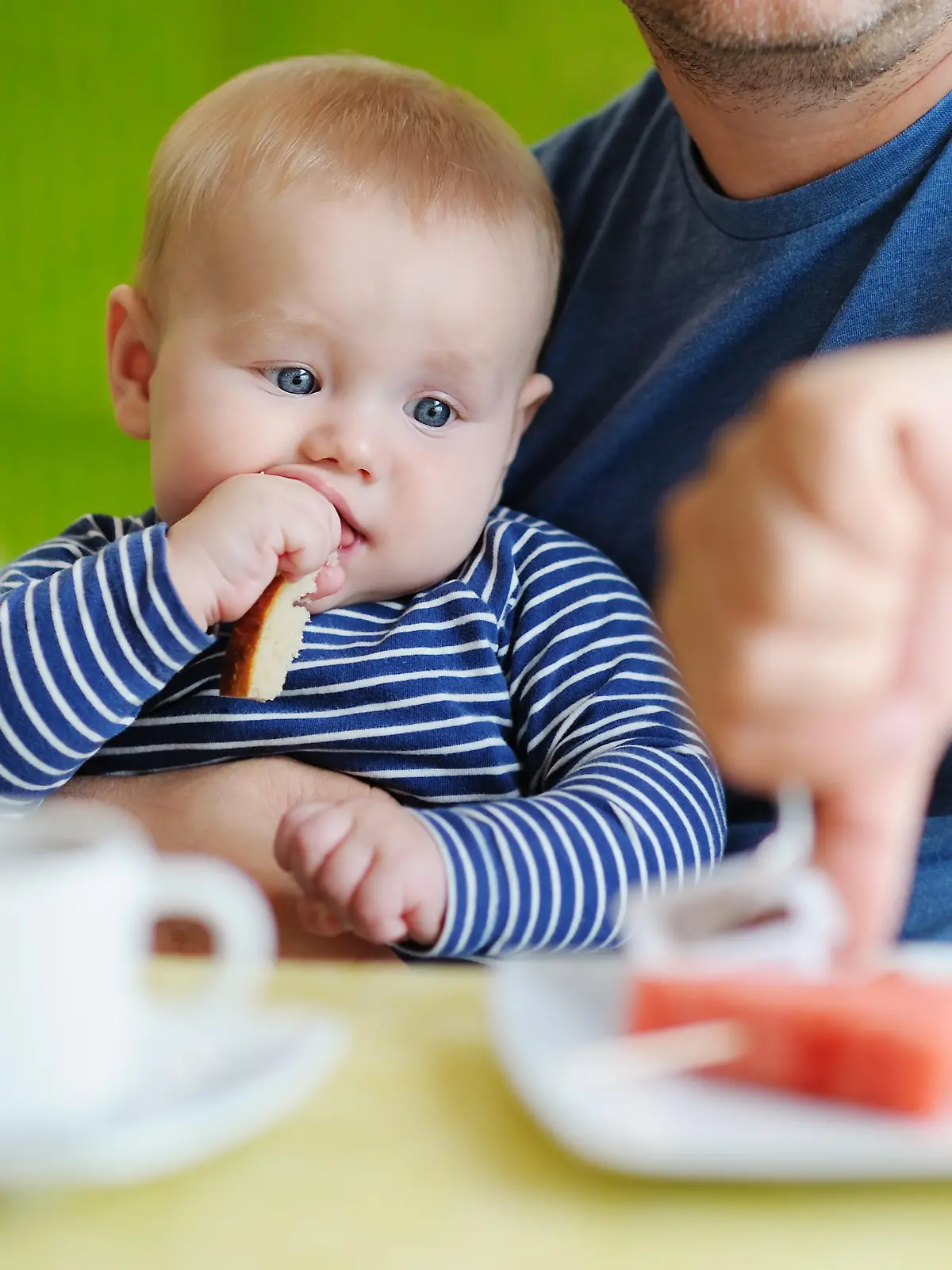 Portrait of little baby boy eating piece of bread