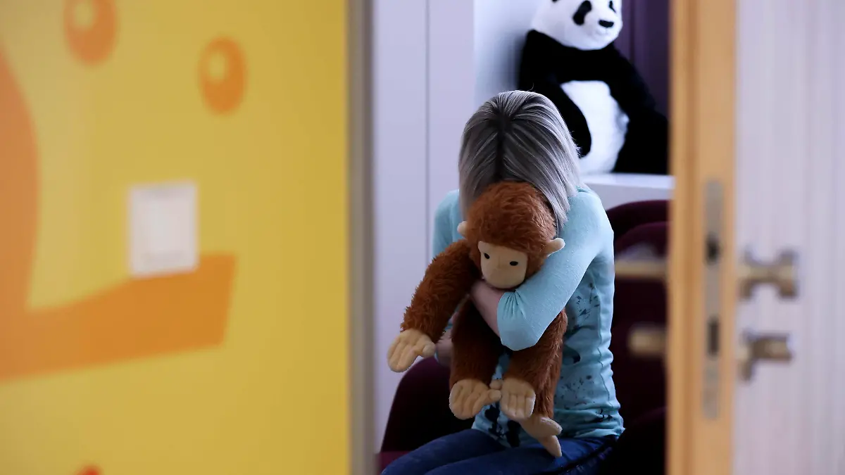 PRODUKTION - 14.03.2022, Sachsen, Leipzig: ILLUSTRATION - Eine junge Frau sitzt mit einem Kuscheltier im Arm in einem Raum des Childhood House, in dem Kinder und Jugendliche, die von Missbrauchs betroffen sind, vernommen werden können (gestellte Szene). (zu dpa: «Kindesmissbrauch im Netz: Die EU-Kommission will strengere Regeln») Foto: Jan Woitas/dpa +++ dpa-Bildfunk +++