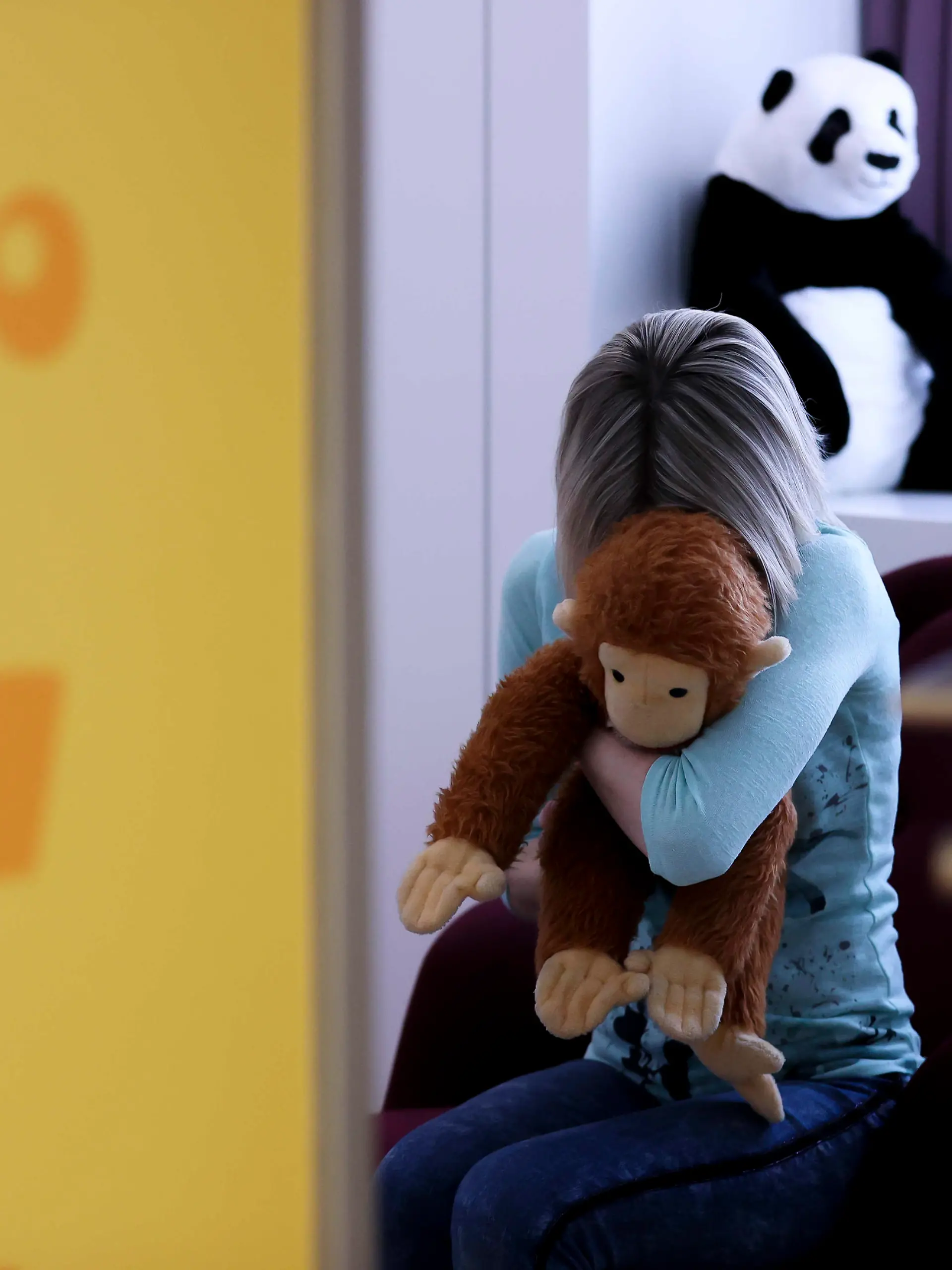 PRODUKTION - 14.03.2022, Sachsen, Leipzig: ILLUSTRATION - Eine junge Frau sitzt mit einem Kuscheltier im Arm in einem Raum des Childhood House, in dem Kinder und Jugendliche, die von Missbrauchs betroffen sind, vernommen werden können (gestellte Szene). (zu dpa: «Kindesmissbrauch im Netz: Die EU-Kommission will strengere Regeln») Foto: Jan Woitas/dpa +++ dpa-Bildfunk +++