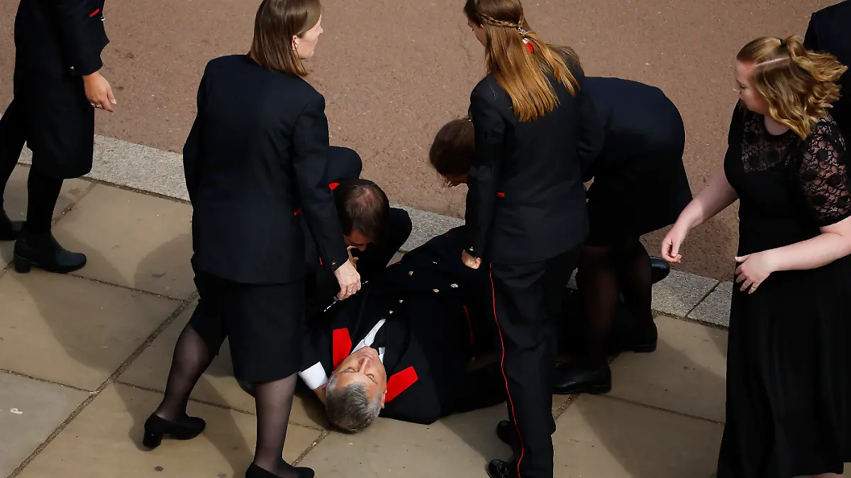 LONDON, ENGLAND - SEPTEMBER 19: A Buckingham Palace household staff person collapses outside Buckingham Palace after paying their respects during the State Funeral of Queen Elizabeth II on September 19, 2022 in London, England. Elizabeth Alexandra Mary Windsor was born in Bruton Street, Mayfair, London on 21 April 1926. She married Prince Philip in 1947 and ascended the throne of the United Kingdom and Commonwealth on 6 February 1952 after the death of her Father, King George VI. Queen Elizabeth II died at Balmoral Castle in Scotland on September 8, 2022, and is succeeded by her eldest son, King Charles III.  (Photo by Chip Somodevilla/Getty Images)
