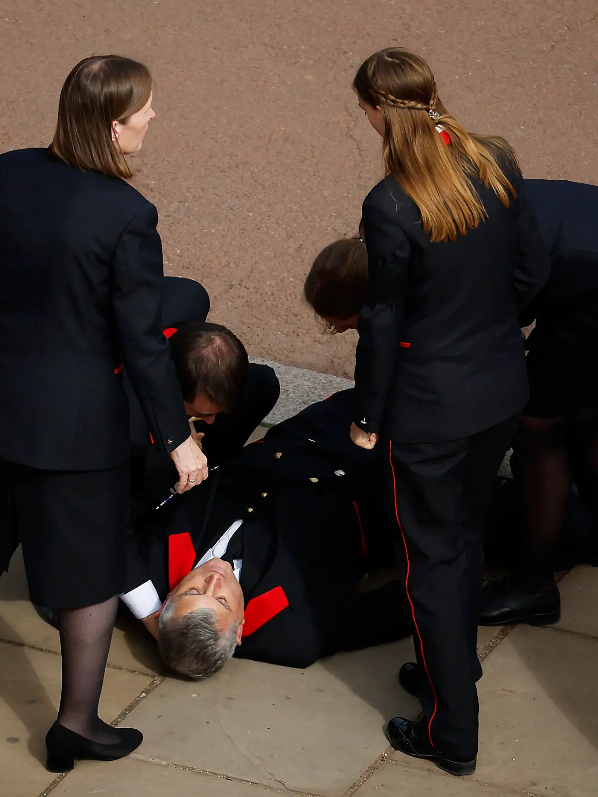 LONDON, ENGLAND - SEPTEMBER 19: A Buckingham Palace household staff person collapses outside Buckingham Palace after paying their respects during the State Funeral of Queen Elizabeth II on September 19, 2022 in London, England. Elizabeth Alexandra Mary Windsor was born in Bruton Street, Mayfair, London on 21 April 1926. She married Prince Philip in 1947 and ascended the throne of the United Kingdom and Commonwealth on 6 February 1952 after the death of her Father, King George VI. Queen Elizabeth II died at Balmoral Castle in Scotland on September 8, 2022, and is succeeded by her eldest son, King Charles III.  (Photo by Chip Somodevilla/Getty Images)