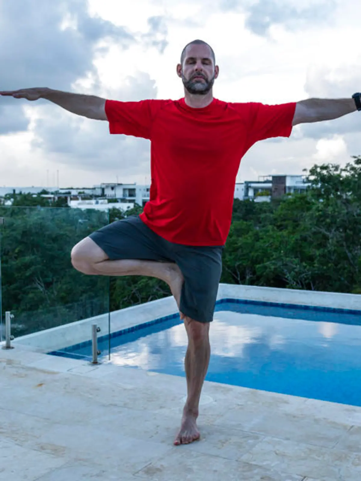 He balances in tree pose, while on a tropical holiday at a luxury hotel