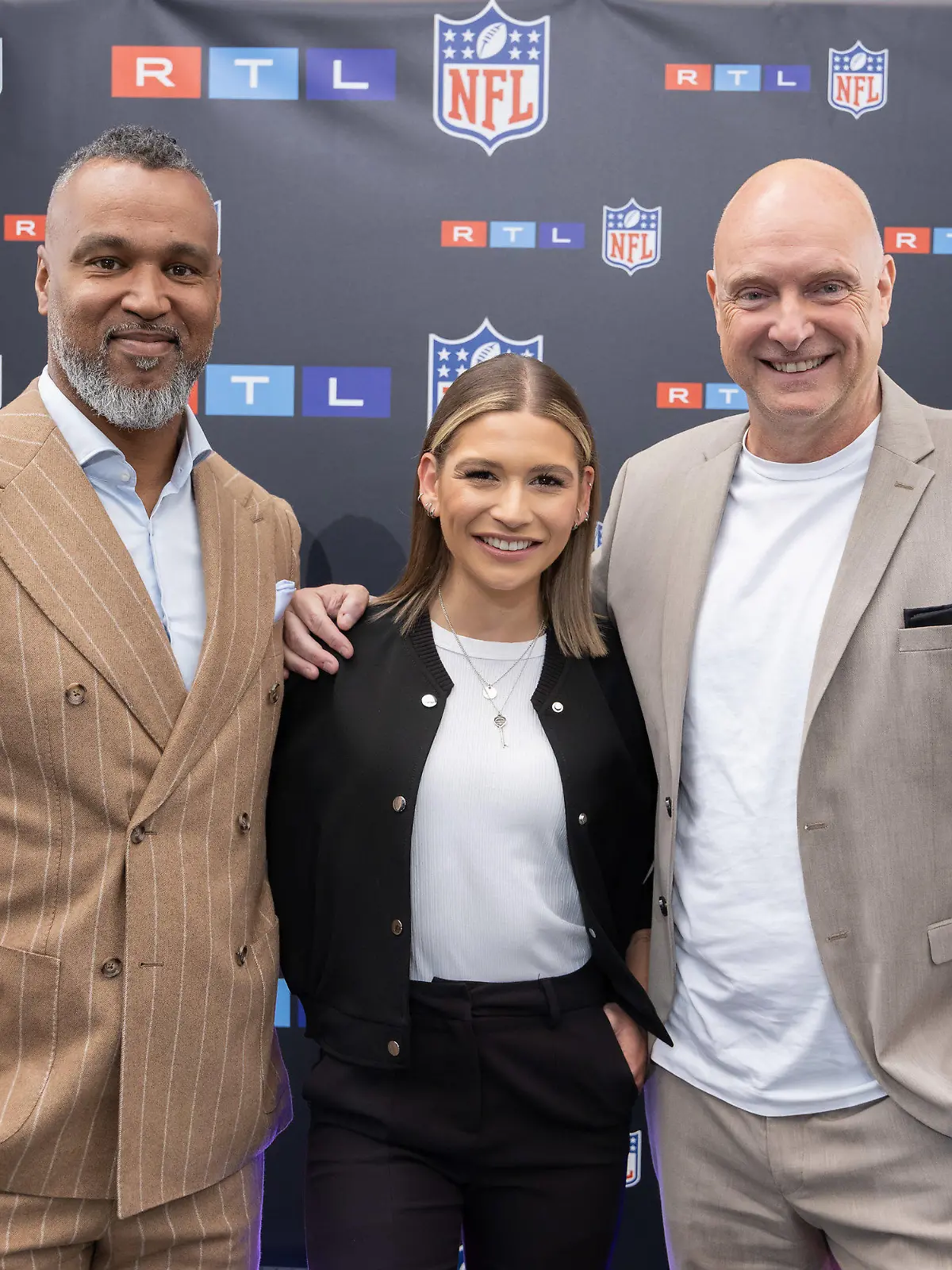ARCHIV - 26.05.2023, Hessen, Frankfurt am Main: TV-Experte Patrick Esume (l) und die TV-Moderatoren Jana Wosnitza und Frank Buschmann stehen beim Presseevent zusammen. Die RTL-Gruppe beginnt ihre NFL-Übertragungen. (zu dpa: «Erste Football-Übertragung bei neuem Sender») Foto: Jürgen Kessler/dpa +++ dpa-Bildfunk +++