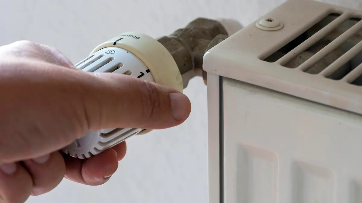 ILLUSTRATION - Eine Hand regelt das Thermostat einer Heizung. Verbraucher müssen sich darauf einstellen, dass die Kosten für Heizöl und Erdgas weiter ansteigen.