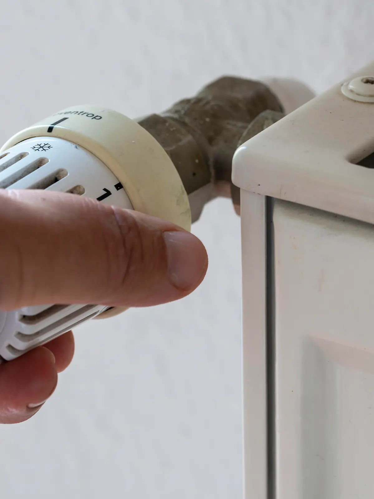 ILLUSTRATION - Eine Hand regelt das Thermostat einer Heizung. Verbraucher müssen sich darauf einstellen, dass die Kosten für Heizöl und Erdgas weiter ansteigen.